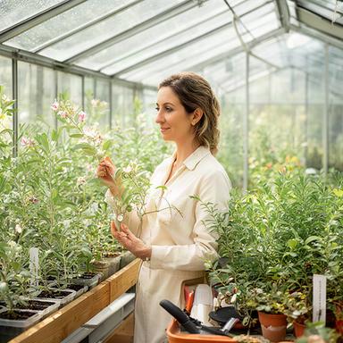 Lucia mentre esamina foglie e fiori in una serra luminosa